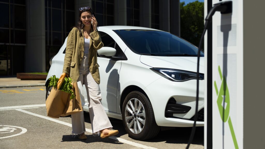 Jeune dame au téléphone pendant que sa voiture électrique recharge